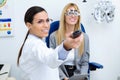 Woman optometrist with trial frame checking patient`s vision at eye clinic. Selective focus on doctor.