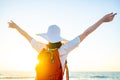 woman with orange backpack with rainbow straps rainbow and hat at sea beach at sunset Royalty Free Stock Photo