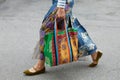 Woman with orange and green floral design bag walking before Arthur Arbesser fashion show,