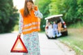 Woman in orange reflective vest installing red warning triangle Royalty Free Stock Photo