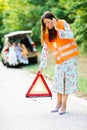 Woman in orange reflective vest installing red warning triangle Royalty Free Stock Photo