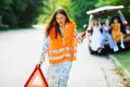 Woman in orange reflective vest installing red warning triangle Royalty Free Stock Photo