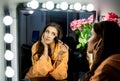 Woman in orange robe doing her makeup and wathching in mirror