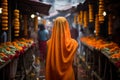 a woman in an orange robe walks through a flower market