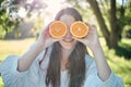 Woman, orange slice and eye pose in outdoor park with natural summer sunshine ray flare. Happy caucasian girl holding Royalty Free Stock Photo