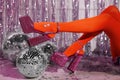 Woman in orange tights and pink high heeled shoes among disco balls indoors, closeup Royalty Free Stock Photo
