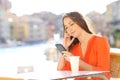 Woman in orange uses a smart phone in a coffee shop