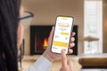 Woman ordering pizza online with a smartphone app in a cozy room by the fireplace Royalty Free Stock Photo