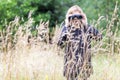 Woman ornithologist studying birds with binocular, vanished out of sight in high grass