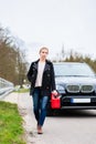 Woman out of fuel with car starting walking towards next gas station Royalty Free Stock Photo