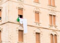 Woman out the window of her old apartment building hanging her laundry to dry