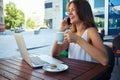 Woman in outdoor cafÃÂ© drinking coffee while talking on the phone and working on laptop Royalty Free Stock Photo