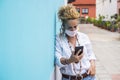 Woman outdoor in the street useing modern phone and wearing protection mask -. coronavirus and covid-19 related new normality