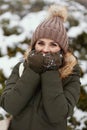 woman outdoors in park in winter warming cold hands with breath
