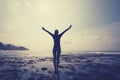 Woman outstretched arms reaching the sky at Sunrise on the seaside reef