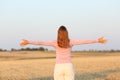 Woman outstretching arms in harvested field Royalty Free Stock Photo