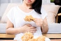 Asian woman overeating fried chicken have a stomachache, indigestion because of eating too much, or binge eating disorder