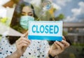 Woman owner with face mask closed store, effect of coronavirus COVID-19 pandemic