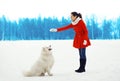 Woman owner trains white Samoyed dog outdoors in winter