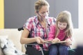 Woman with an oxygen mask and in wheelchair is reading book with little girl