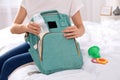 Woman packing baby accessories into maternity backpack on bed Royalty Free Stock Photo