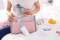 Woman packing baby accessories into maternity bag on bed Royalty Free Stock Photo