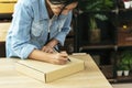 Woman packing box on table checking goods package delivery shipping to customer. Asian woman startup small business at home office