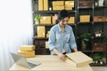 Woman packing box on table checking goods package delivery shipping to customer. Asian woman startup small business at home office