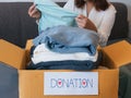 Woman packing clothes into a cardboard box for donation Royalty Free Stock Photo