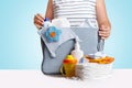 Woman packing diaper bag on blue background.