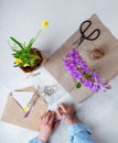 Woman packing spring potted flowers as gifts, writing postcards. Top view, portrait orientation