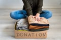 Woman packing used clothes into cardboard donation box