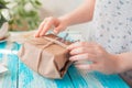 A woman packs a parcel in craft paper wrapped with twine with dried flowers. Hands close-up. Concept of receiving and