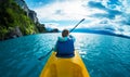 Woman paddles kayak in the lake with turquoise water Royalty Free Stock Photo