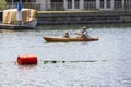 A woman paddling a small boat with her child surrounded by rippling ocean water at Horny Corner Beach in Long Beach California