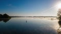 Woman paddling on SUP board on beautiful lake during sunset or sunrise, standing up paddle boarding Royalty Free Stock Photo