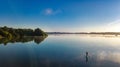 Woman paddling on SUP board on beautiful lake during sunset or sunrise, standing up paddle boarding