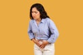 Woman with a pained expression, clutching her abdomen, possibly experiencing stomach pain