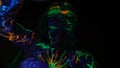 A woman painted with fluorescent paint in the ultraviolet turns the camera