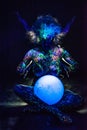 A woman painted with fluorescent powder holds a spherical lamp. Closeup of the legs of a girl's hands with colored body