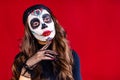 woman with painted skull on her face for Mexico D a de Muertos Mexican traditional ritual in red studio background