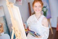 Woman painter holding palette with oil paints in art studio