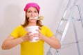 A woman painter holds a brush in her teeth to paint the walls