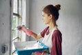 woman painter makes home repairs near window interior