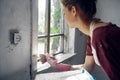 woman painter makes home repairs near window interior