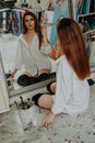 Woman painter sitting on the floor in front of mirror. Art studio interior Royalty Free Stock Photo