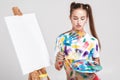 woman painter soiled in colorful paint draws on canvas.