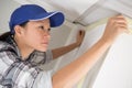 woman painter worker protecting ceiling moulding with masking tape