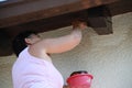 A woman painting with brush a wooden roof of a house