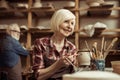 Woman painting clay pot with senior potter